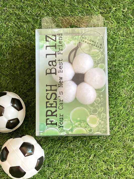 Fresh Ballz car air freshner in black and white colours in flower shape. Laying on grass with decorative soccer  balls.