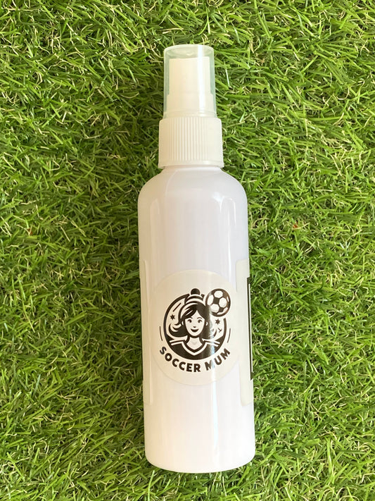 White spray bottle with Soccer Mum logo, laying on the grass